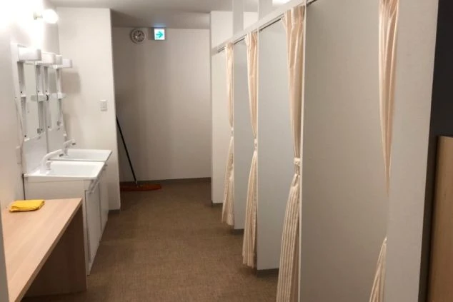 明るい空間に、白い洗面台が2つ並び、その上には鏡と収納棚が設置されている画像。リゾートバイトの寮に完備された、スタッフが共同で使用する清潔な洗面所のイメージ。