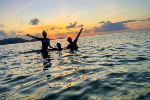 オレンジ色に染まる夕日を浴びながら、海で楽しむリゾートバイトの仲間たち。仕事の後に、こんな感動的な景色が見られるのも魅力の一つです。