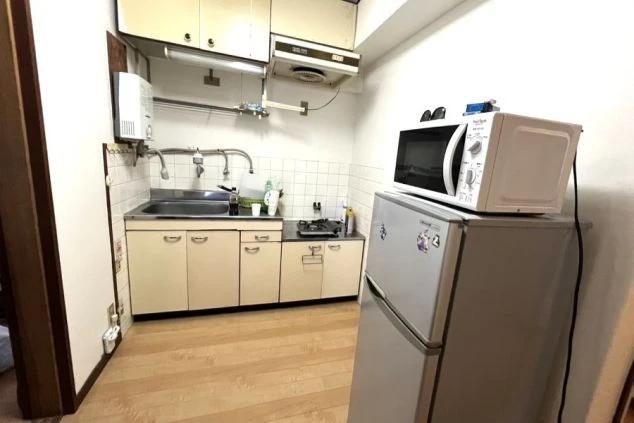 リゾートバイトのカップル寮のキッチン。ガスコンロ、シンク、冷蔵庫、電子レンジが備え付けられ、自炊が可能な設備の画像。