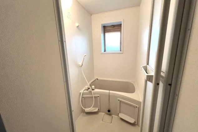 リゾートバイトのカップル寮にあるバスルーム。浴槽とシャワーが一体となった、清潔な設備の画像。