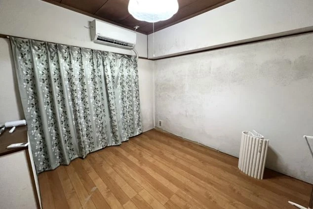 リゾートバイトの寮の洋室。フローリングの床にエアコンとカーテンが備え付けられた広々とした部屋。