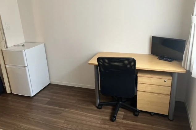 リゾートバイトの社員寮の部屋に備え付けられている家電のイメージ画像。テレビと冷蔵庫、机が写っている。