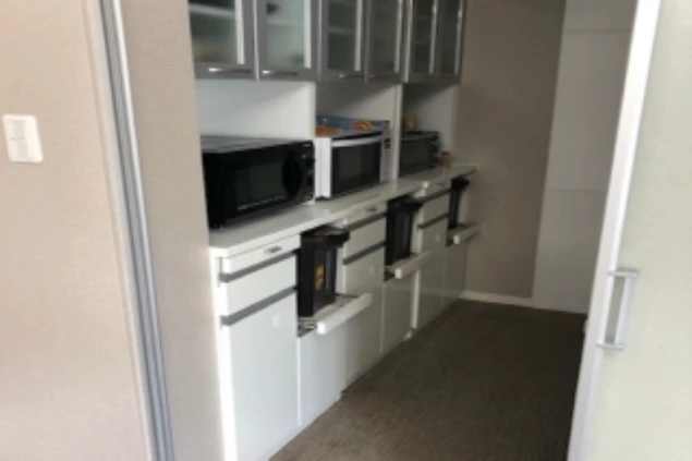 寮のキッチン。複数の電子レンジとトースター、収納棚が並ぶ共用スペースが映る。	