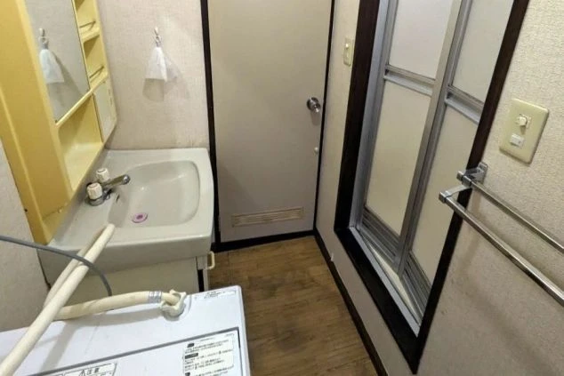 ゾートバイトのシェア寮にある共用ランドリースペースと洗面台。洗濯機が完備されており、長期滞在でも快適に過ごせます。住み込みのリゾートバイトを探している方向けの寮情報。