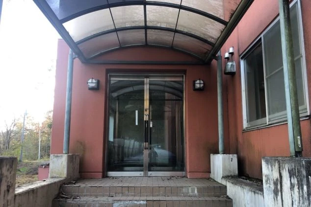 寮の入り口。ガラスのドアとひさしがあり、壁は赤茶色をしています。