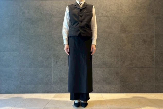 夕食時の制服を着た人物。白いシャツに黒いベストとロングエプロンを着用している。