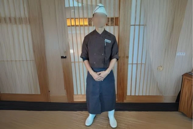 茶色の上着に紺色のエプロン、コック帽と白い長靴を着用した、和食レストランの調理スタッフの制服。