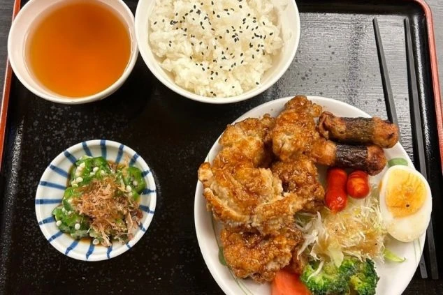 ご飯、唐揚げ、おかず、サラダ、スープがバランス良く盛り付けられた、リゾートバイトの充実した賄い画像。