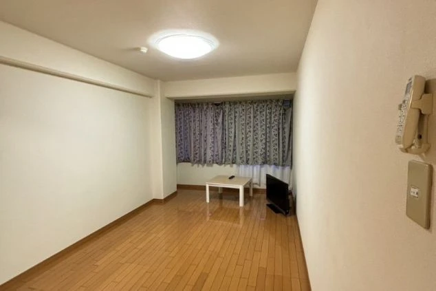 リゾートバイトの個室寮の室内。フローリングの床にローテーブル、テレビが置かれた、広々としてシンプルな寮の部屋の画像。