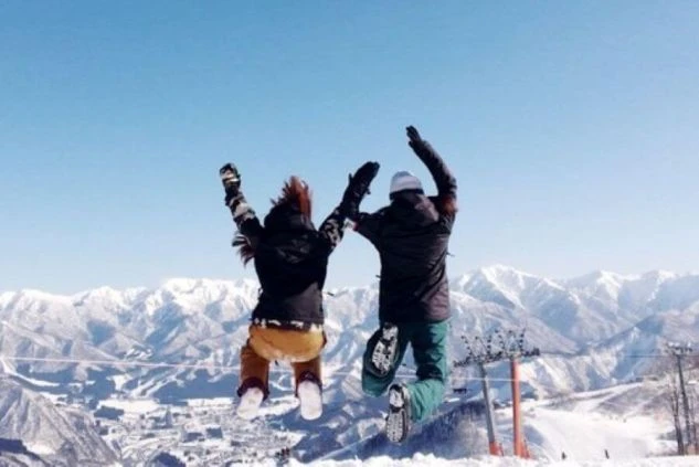 ワクトリでリゾートバイトをしたスタッフが撮影した、雄大な雪山を背景に、ジャンプして喜ぶ2人。