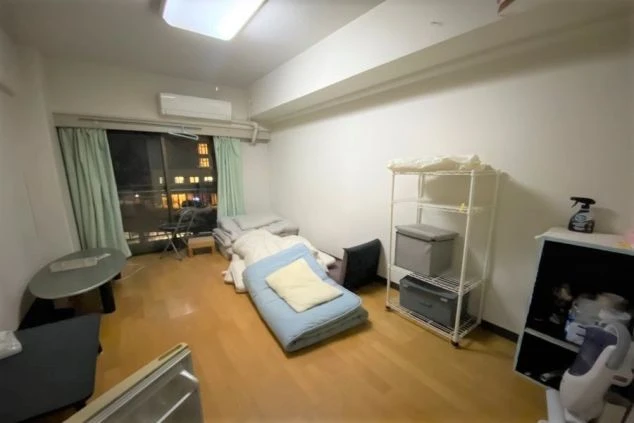 リゾートバイトの個室寮の室内。フローリングの部屋に布団、テーブル、ラックが置かれ、生活に必要な家具が揃っている様子を伝える画像。