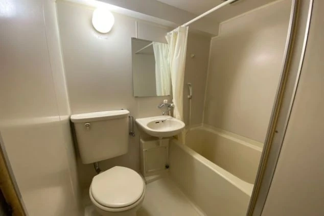 リゾートバイトの個室寮にあるユニットバス。浴槽、洗面台、トイレが一体となった、プライベートな空間で利用できる設備の画像。