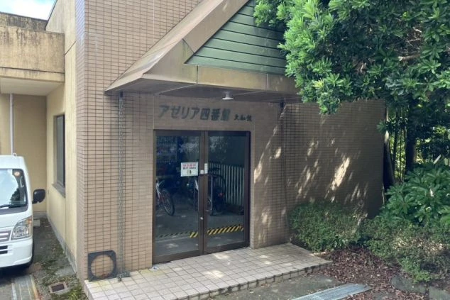 リゾートバイト寮の外観。「アゼリア四番館」と書かれた建物の入り口。落ち着いた雰囲気の中で生活できる、住み込み寮の画像。