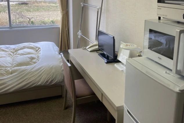 快適な生活を送るための寮の個室。ベッド、デスク、テレビ、冷蔵庫、電子レンジが完備