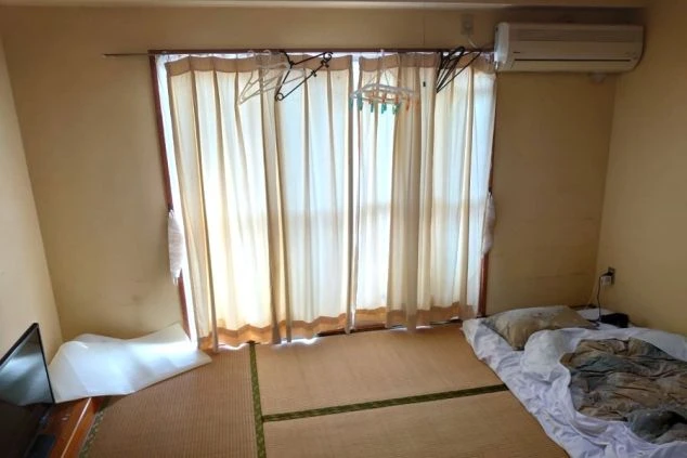 リゾートバイトの個室寮(和室)の画像。大きな窓とカーテン、エアコンが設置されている。