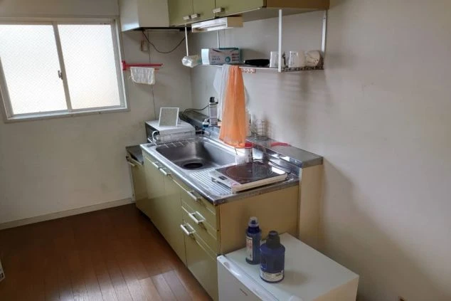 リゾートバイト寮にあるキッチンの画像。自炊可能なIHコンロ、シンク、収納キャビネット、小型冷蔵庫が備わっている。