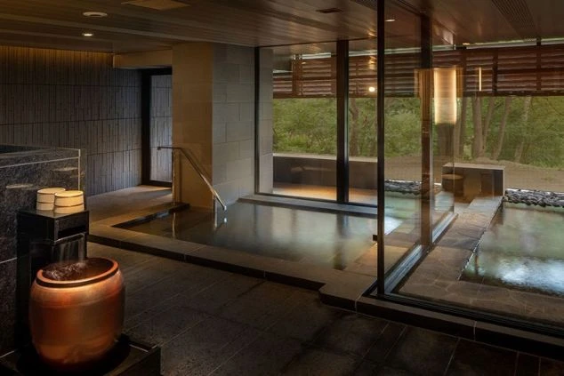 モダンな内装の温泉。室内には大きな湯船と、窓の外に庭園が見える露天風呂がある。