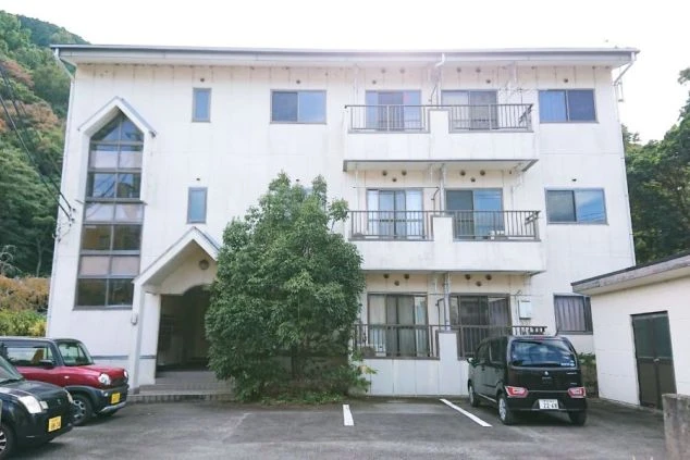 リゾートバイトで住み込める白い寮の外観。駐車場には数台の車が停まっている。