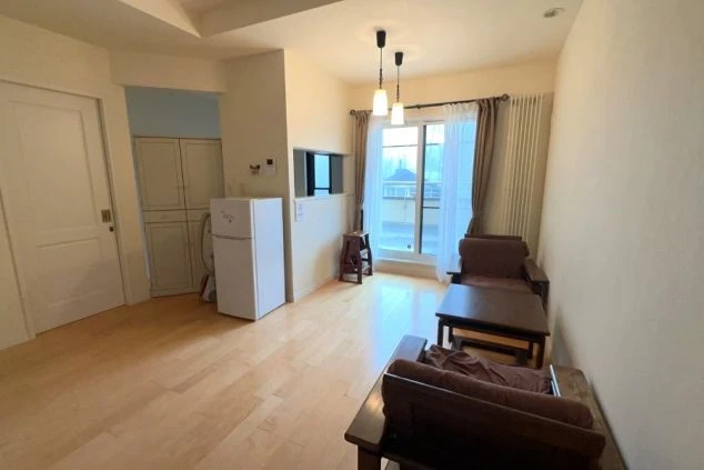 ワクトリの社員が出張で撮影した、リゾートバイトの女子寮の共用リビングスペースの画像。フローリングの広々とした空間に、ソファとテーブル、冷蔵庫が配置されている。