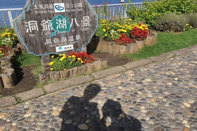 モダンな建物外観。ベージュと濃い色のラインが入った多層階のホテル棟と、エントランス部分のサイン。