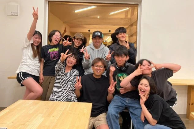 モダンな建物外観。ベージュと濃い色のラインが入った多層階のホテル棟と、エントランス部分のサイン。