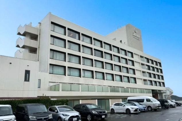 ホテルの建物と駐車場。海沿いに建つ白い建物で、多くの窓が並んでいます。