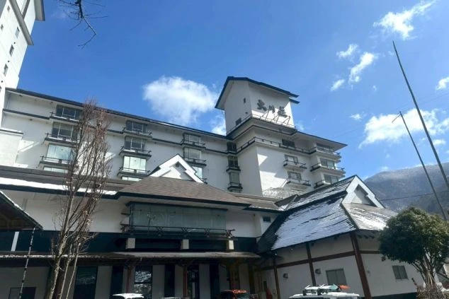 広々とした内湯から窓越しに緑豊かな大自然の景色を眺められる温泉の写真。仕事の疲れを癒したい時にこのような絶景温泉に入れるなど、リゾートバイトの大きな魅力を伝えます。