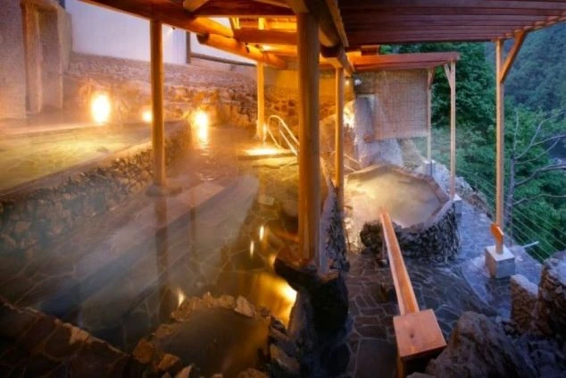 川の流れが見える、自然に囲まれた露天風呂の写真。仕事の疲れを癒したい時に、このような絶景温泉**に入れるなど、リゾートバイトの大きな魅力を伝えます。