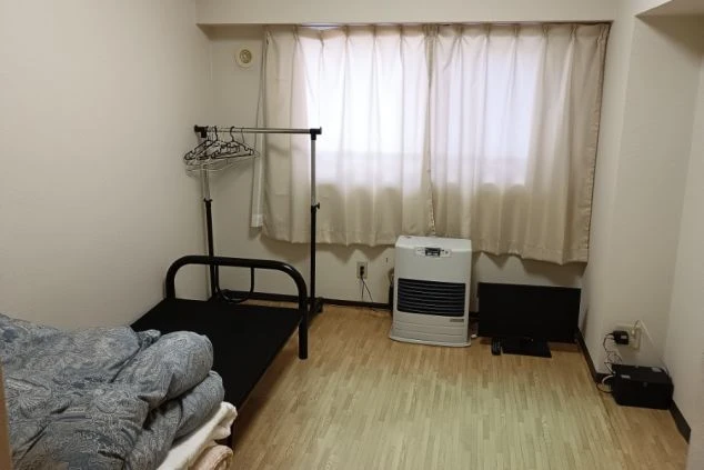 リゾートバイト先の完全個室寮の画像。ベッド、テレビ、ヒーター、ハンガーラックが完備された、プライベートを確保できる快適な居住空間。