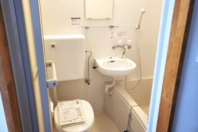 リゾートバイトの個室寮にあるユニットバス。浴槽、洗面台、トイレが一体となった、清潔な設備の画像。