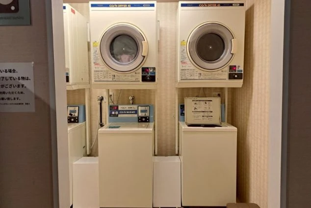 リゾートバイト寮の共用ランドリースペース。洗濯機と乾燥機が設置されており、長期滞在でも衣類の手入れに困らない便利な設備の画像。