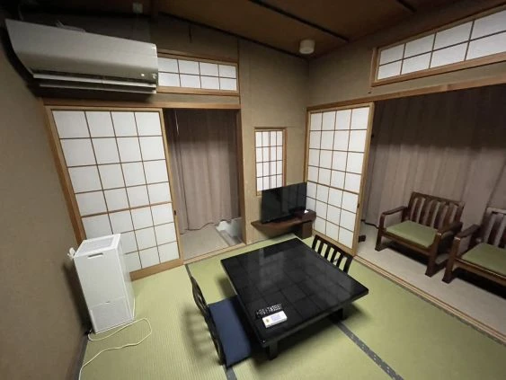 畳の部屋に、こたつテーブルとテレビが設置されている旅館の客室寮の画像。部屋にはエアコンや空気清浄機も完備されている画像。