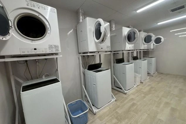 リゾートバイトの寮に完備された、洗濯機と乾燥機が複数台並ぶ清潔な共同ランドリースペースの画像。