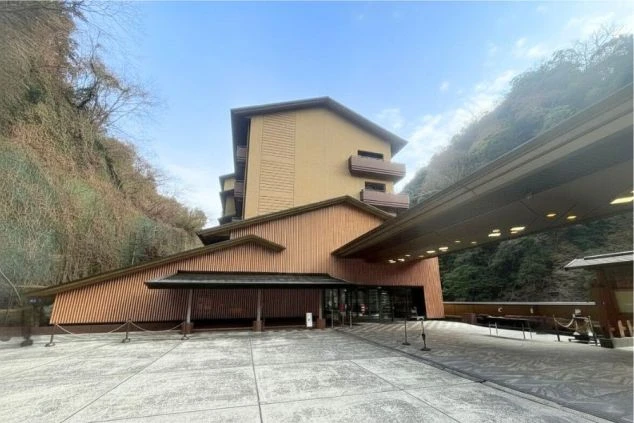 熊本県と大分県の県境に位置する老舗旅館の外観画像。深い緑の山々に囲まれた、和モダンで重厚感のある建物。