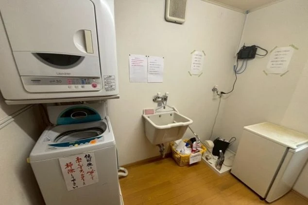 リゾートバイトの寮の共用スペースにある、洗濯機と乾燥機の画像。手前には流し台が備え付けられており、洗濯や簡単な洗い物に利用できる。リゾートバイトの寮の共用スペースの画像。
