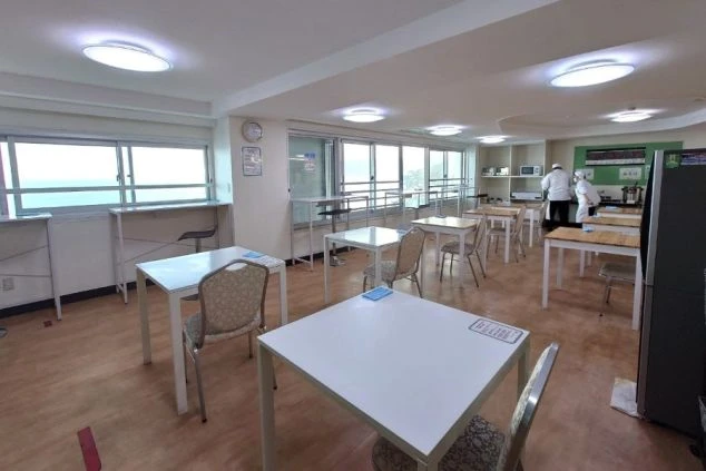 寮の共同食堂。大きな窓からは景色が見え、仕事仲間と楽しく食事する様子。