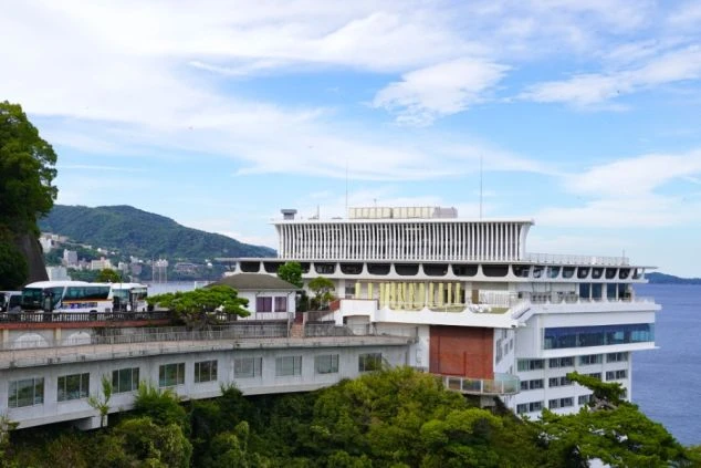 青い海と空を背景に、地形を活かした白い巨大なホテル建築が広がっている。