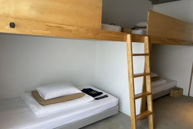 二つのロフトベッドがある寮の部屋。ロフトの下にはマットレスが置かれており、木製のはしごが見える。