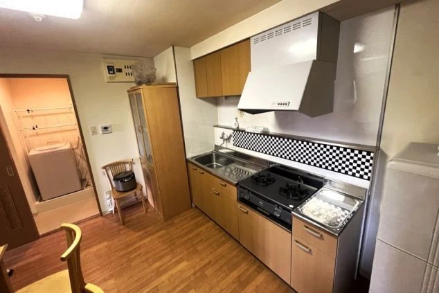 リゾートバイト寮の共用キッチン。ガスコンロ、電子レンジ、ミニ冷蔵庫が備え付けられ、自炊や簡単な調理ができる設備の寮の画像。