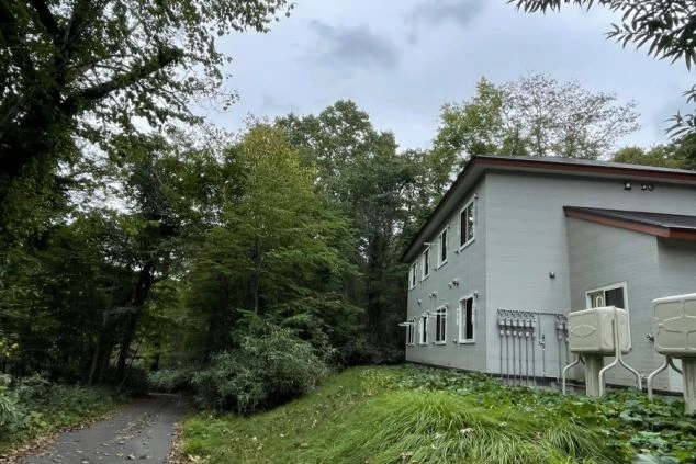 木々に囲まれた2階建ての寮の外観。