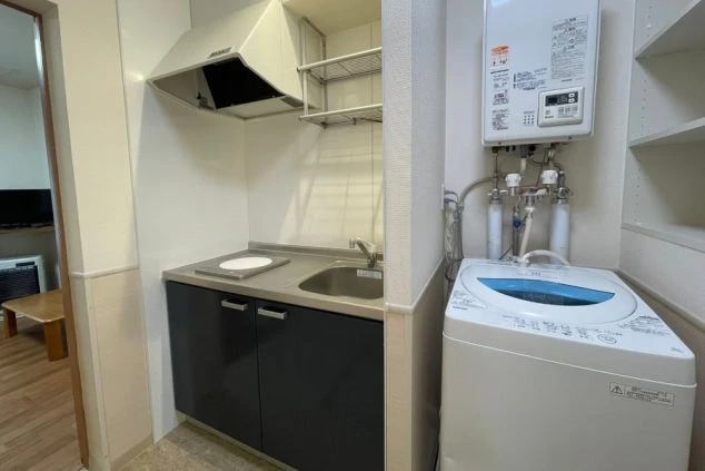 IHコンロ付きのミニキッチンと、その横にある洗濯機。
