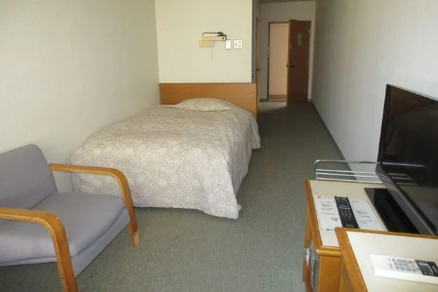 リゾートバイトの男子寮の部屋の画像。ベッド・チェア・TVが見える。