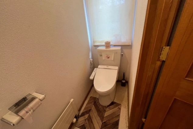 温水洗浄便座付きのトイレ。床には木目調のマットが敷かれている。