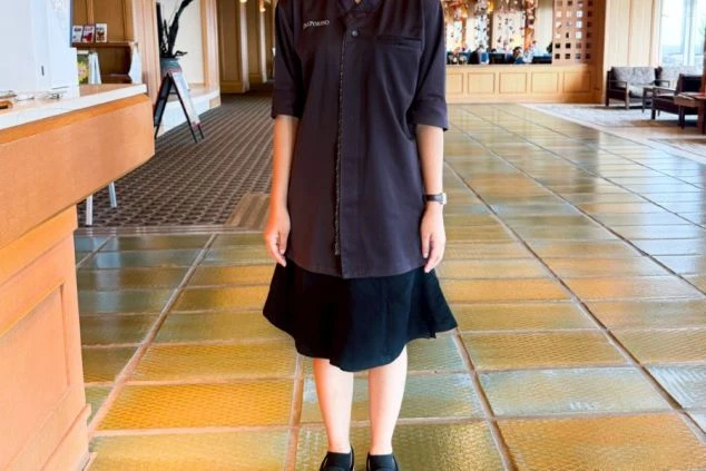 接客係の夏服を着た女性。作務衣のような上着に、黒いスカートを着用している。