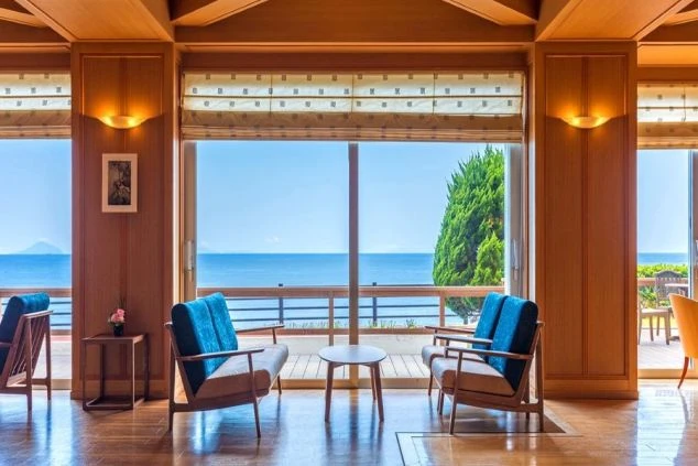 海が見えるホテルのロビー。木製の壁に囲まれた部屋には、青い椅子が置かれている。