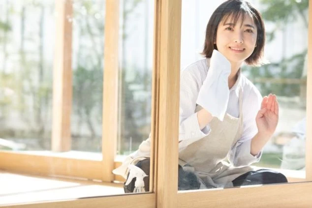 リゾートバイトの従業員が働いている様子を写した画像。笑顔の女性スタッフがエプロンをして窓ガラスを拭いている画像。