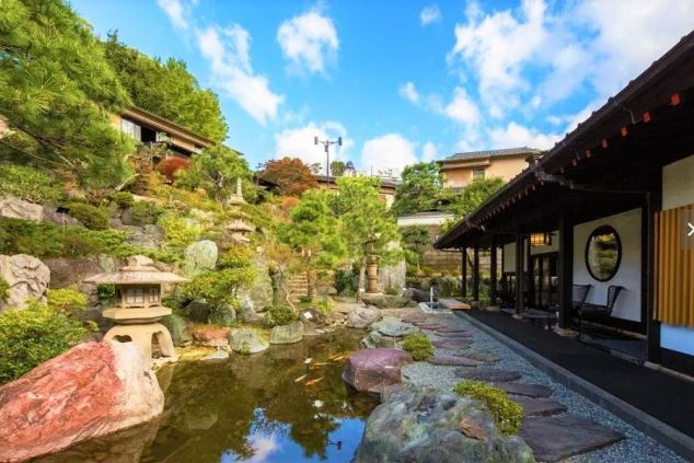 鯉が泳ぐ池と石灯籠が配置された、旅館の美しい日本庭園。リゾートバイトで、日本の伝統的な庭園に囲まれた落ち着いた環境で働きたい方に魅力的な画像。