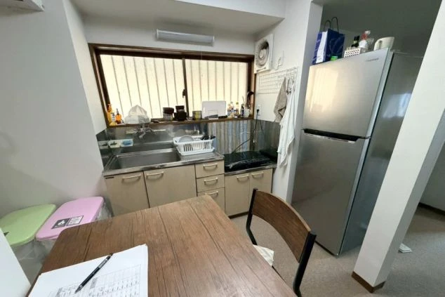 リゾートバイト寮の室内キッチン。大型冷蔵庫やテーブルがあり、仕事終わりや休日に自炊も楽しめる環境。