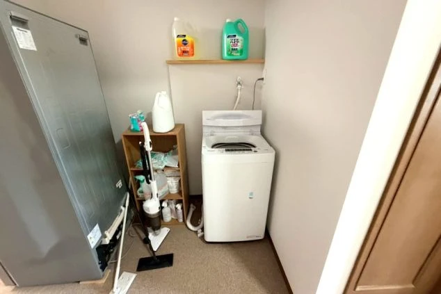 リゾートバイト寮の洗濯機と掃除用品。生活家電や備品が揃い、自分時間を大切にしながら清潔に暮らせる。