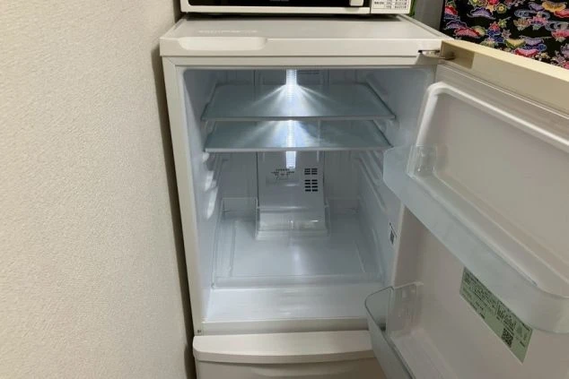 冷蔵庫のドアが開いており、中には棚とドアポケットが見える。